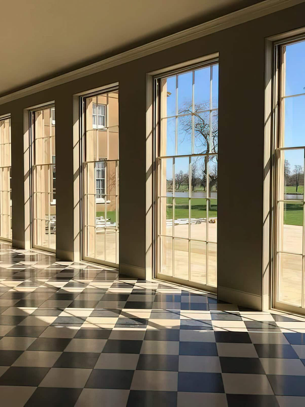 A room with large sash windows and a checkered floor.